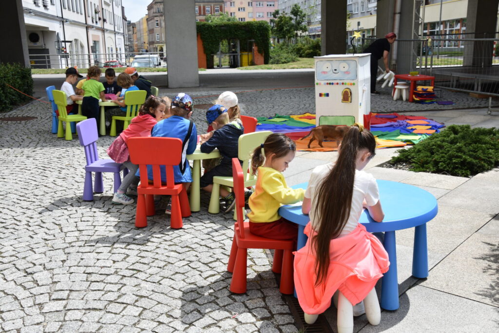 Dzieci rysujące przy kolorowych stolikach