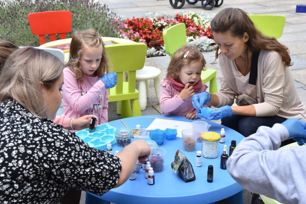 Dzieci na skwerze z dzikami,na warsztatach tworzenia naturalnych mydełek i obrazów z polnych kwiatów