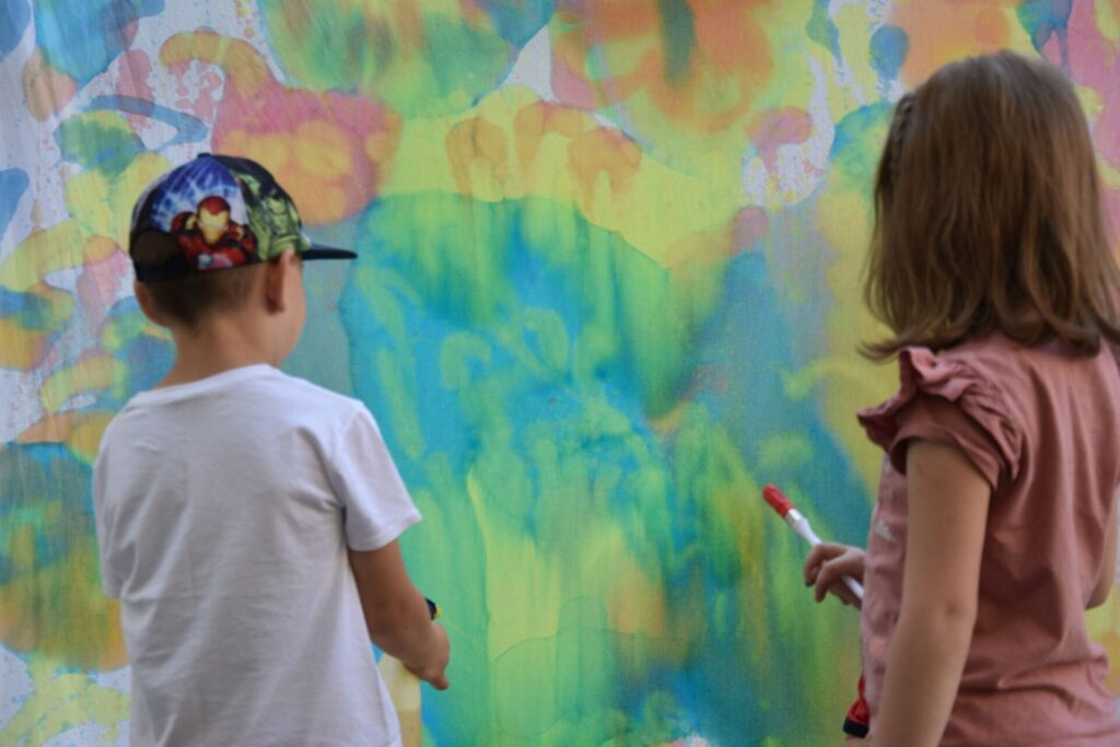 Dzieci na skwerze z dzikami malują eko farbami