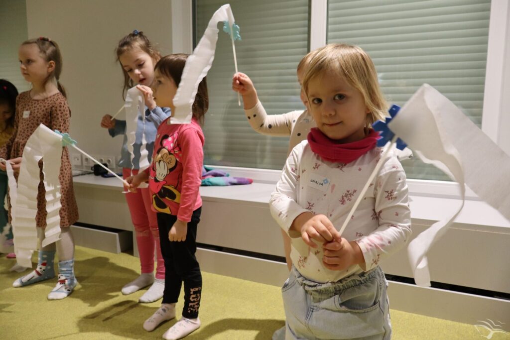 Dzieci stoją i trzymają białe chorągiewki z papieru.