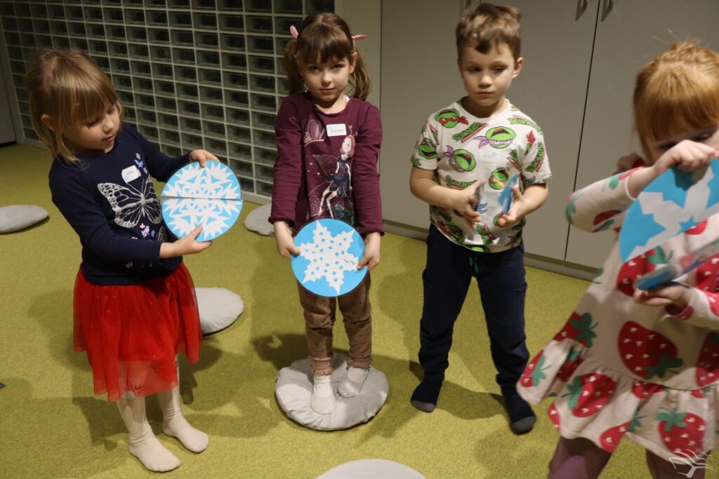 Dzieci stoją i trzymają śnieżynki zrobione z papieru.
