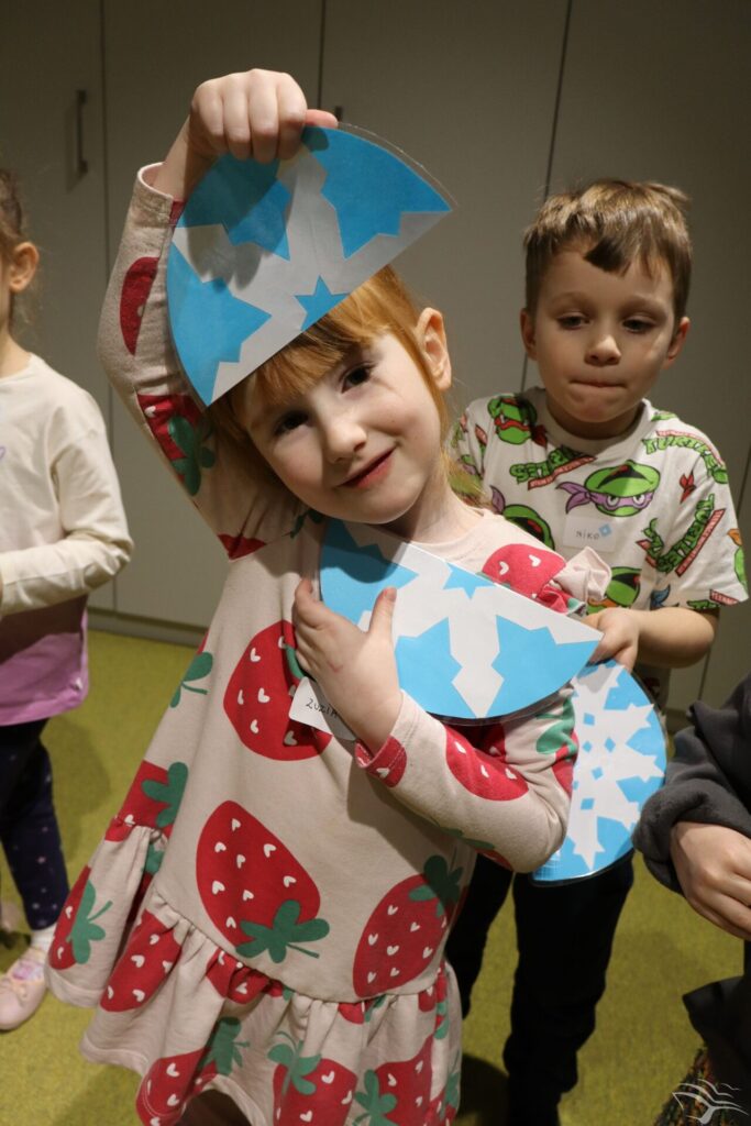 Dzieci stoją i trzymają śnieżynki zrobione z papieru.