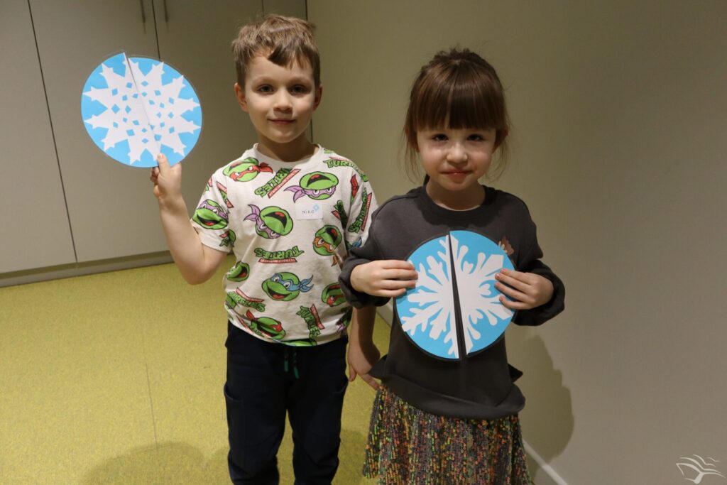 Dzieci stoją i trzymają śnieżynki zrobione z papieru.