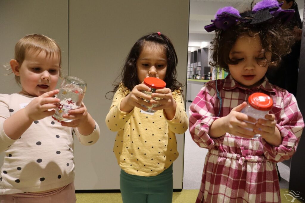 Trzy dziewczynki trzymają w rękach szklane kule zrobione ze słoików.